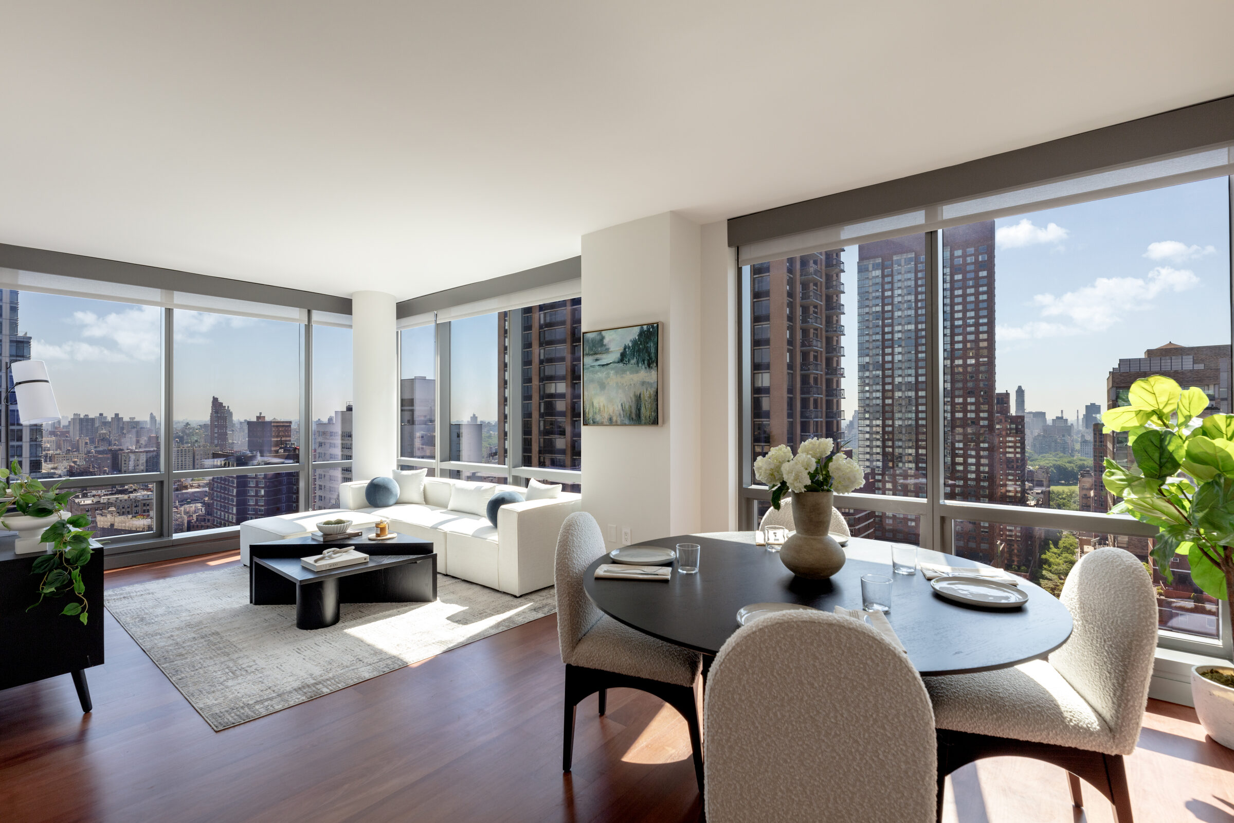 Sunlit corner living and dining room at AIRE with floor-to-ceiling windows and city views