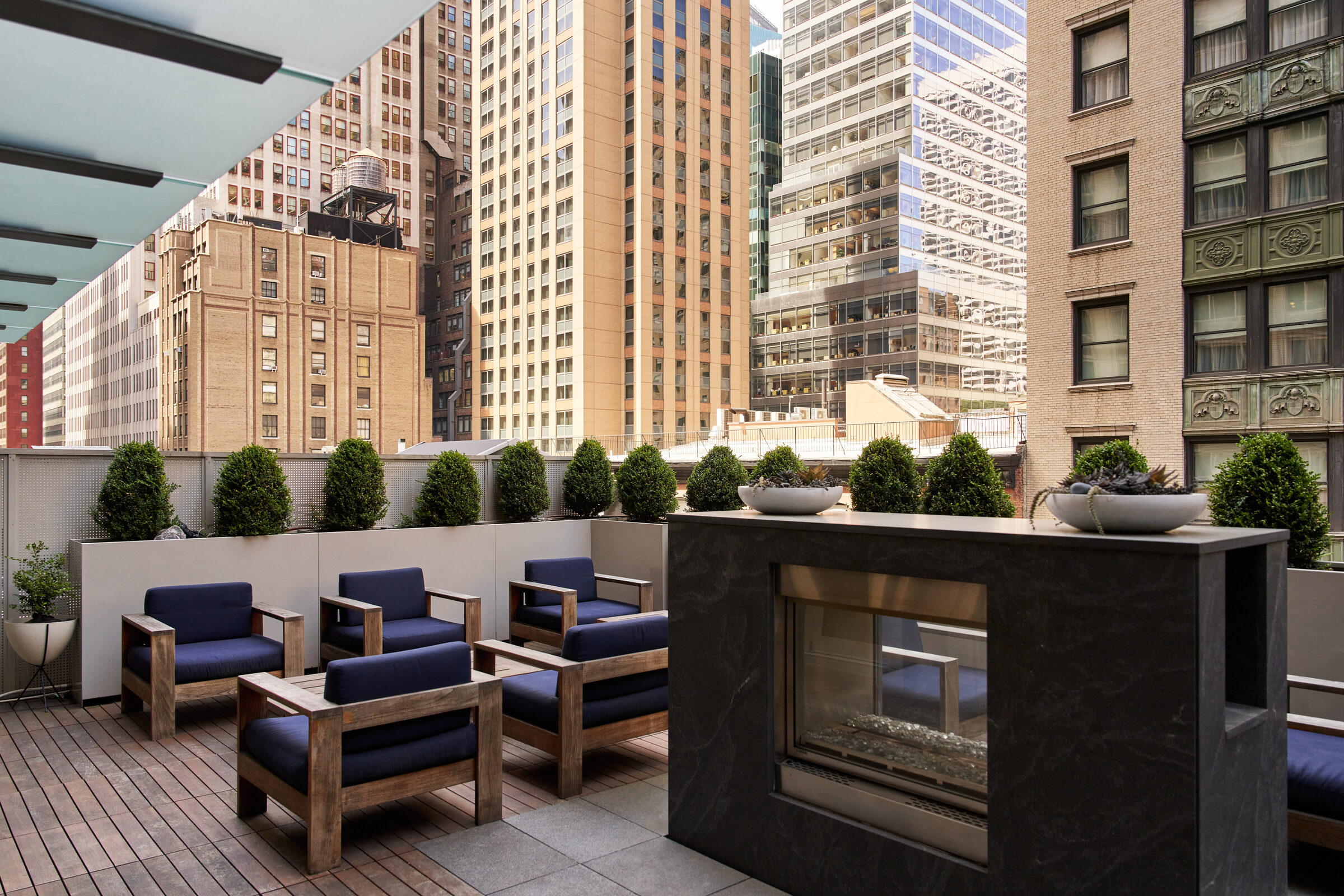 Rooftop terrace at Atlas New York with a fireplace and surrounding city buildings