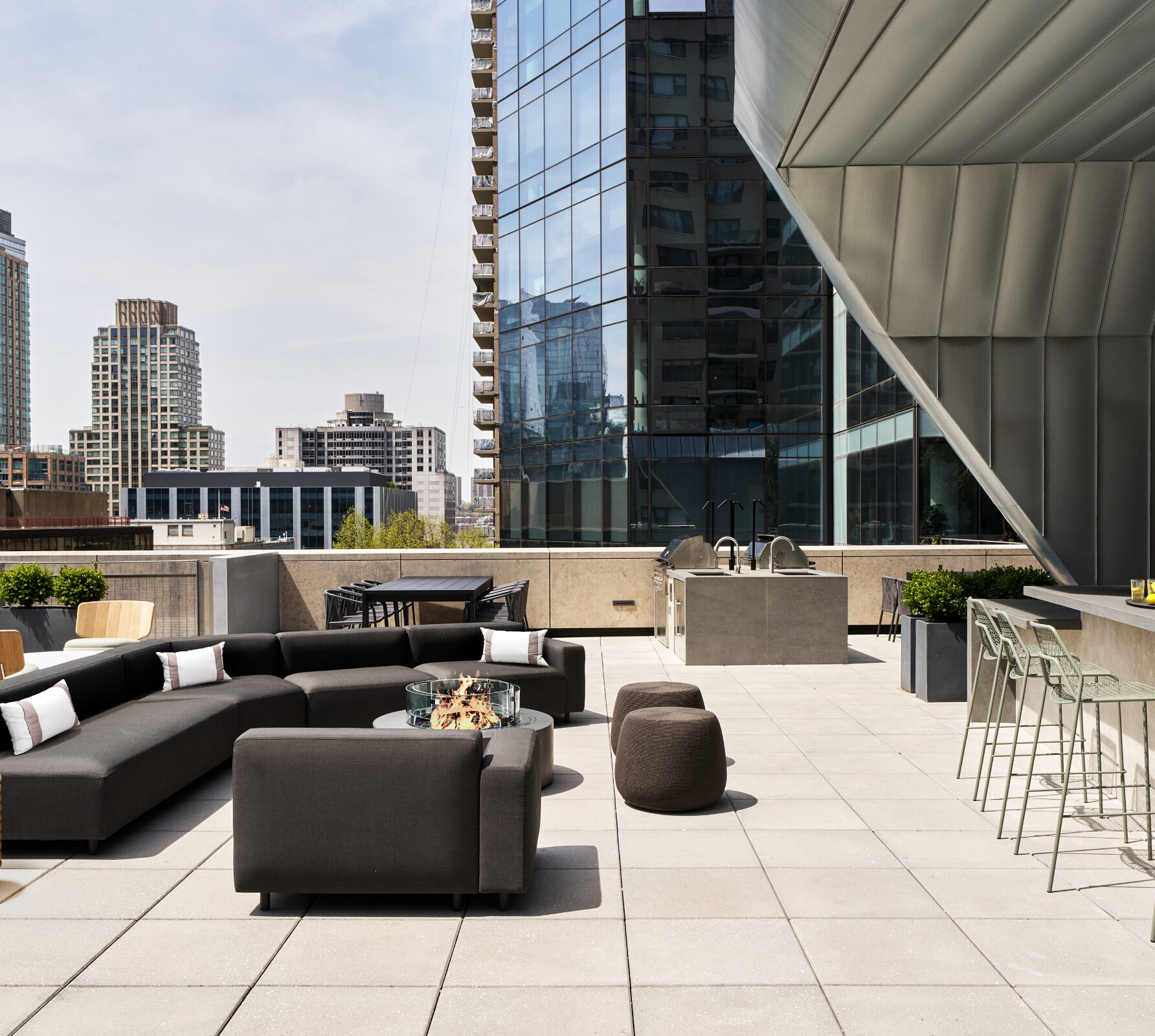 Rooftop terrace at AIRE with a fire pit, outdoor kitchen, and city views