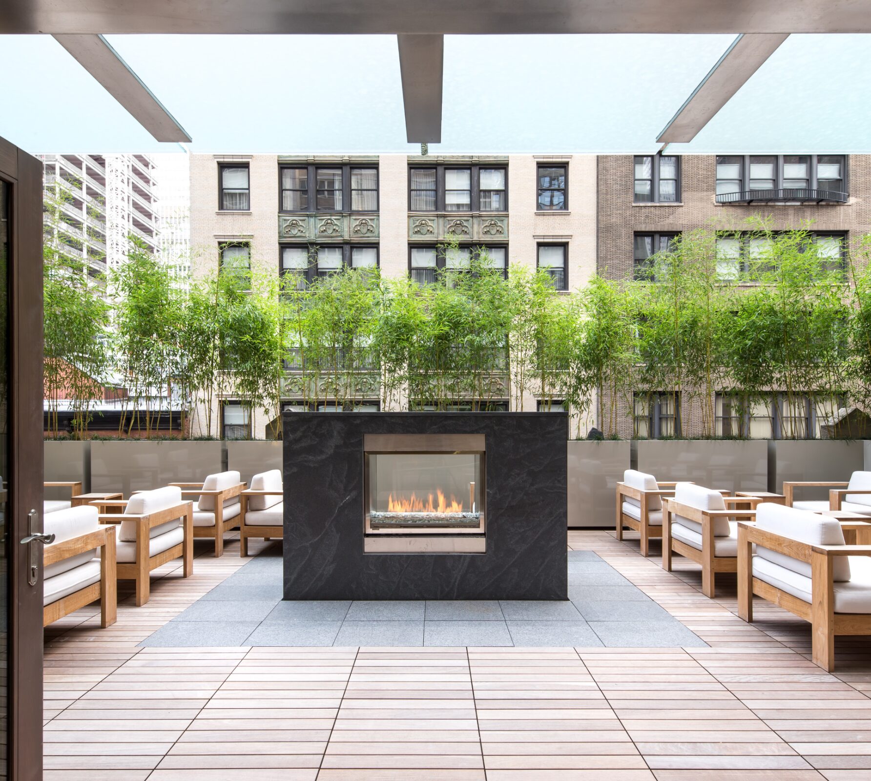 Courtyard terrace at Atlas New York with a fireplace and lounge chairs