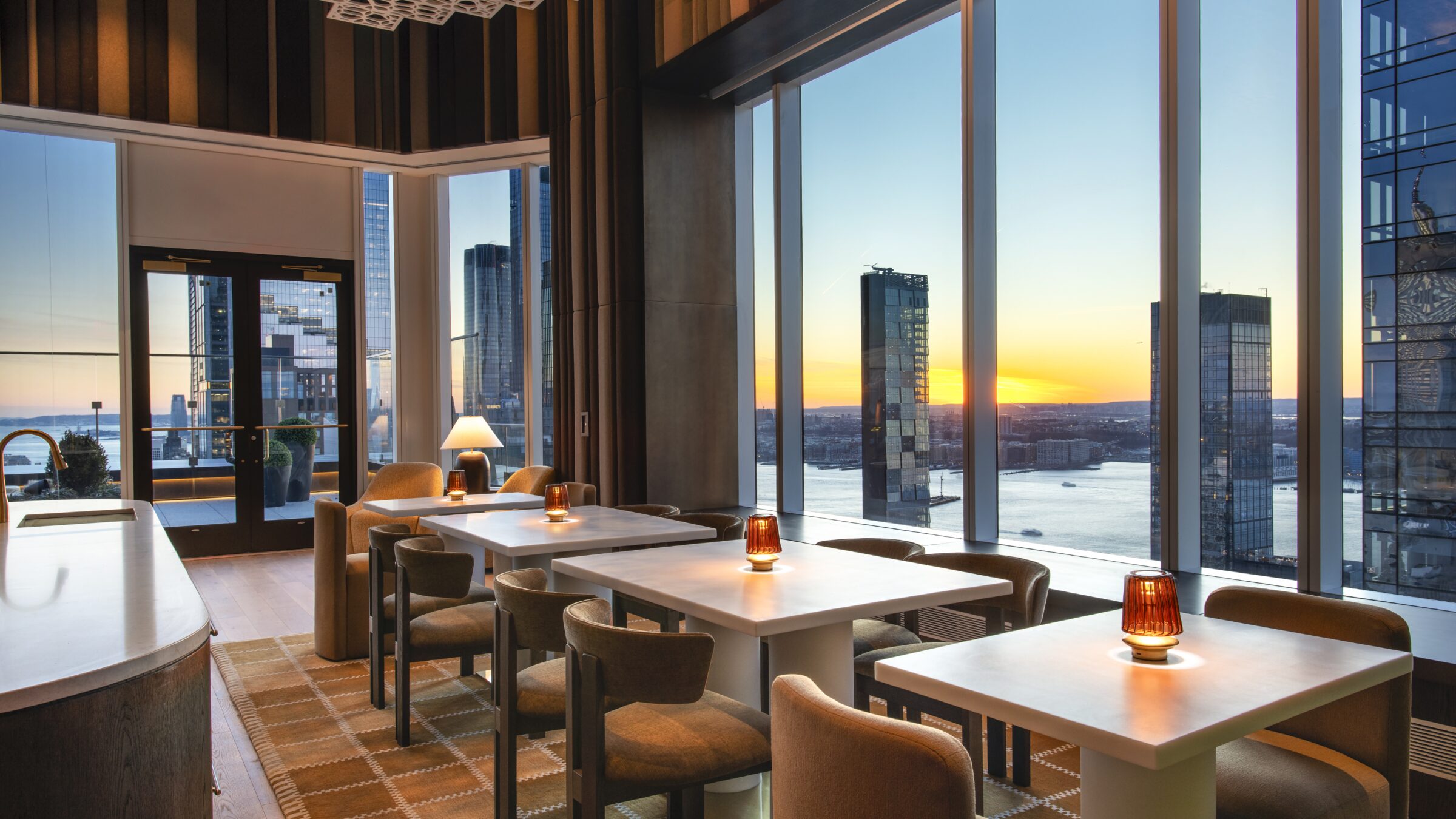 Dining lounge at The Maybury with floor-to-ceiling windows and sunset views