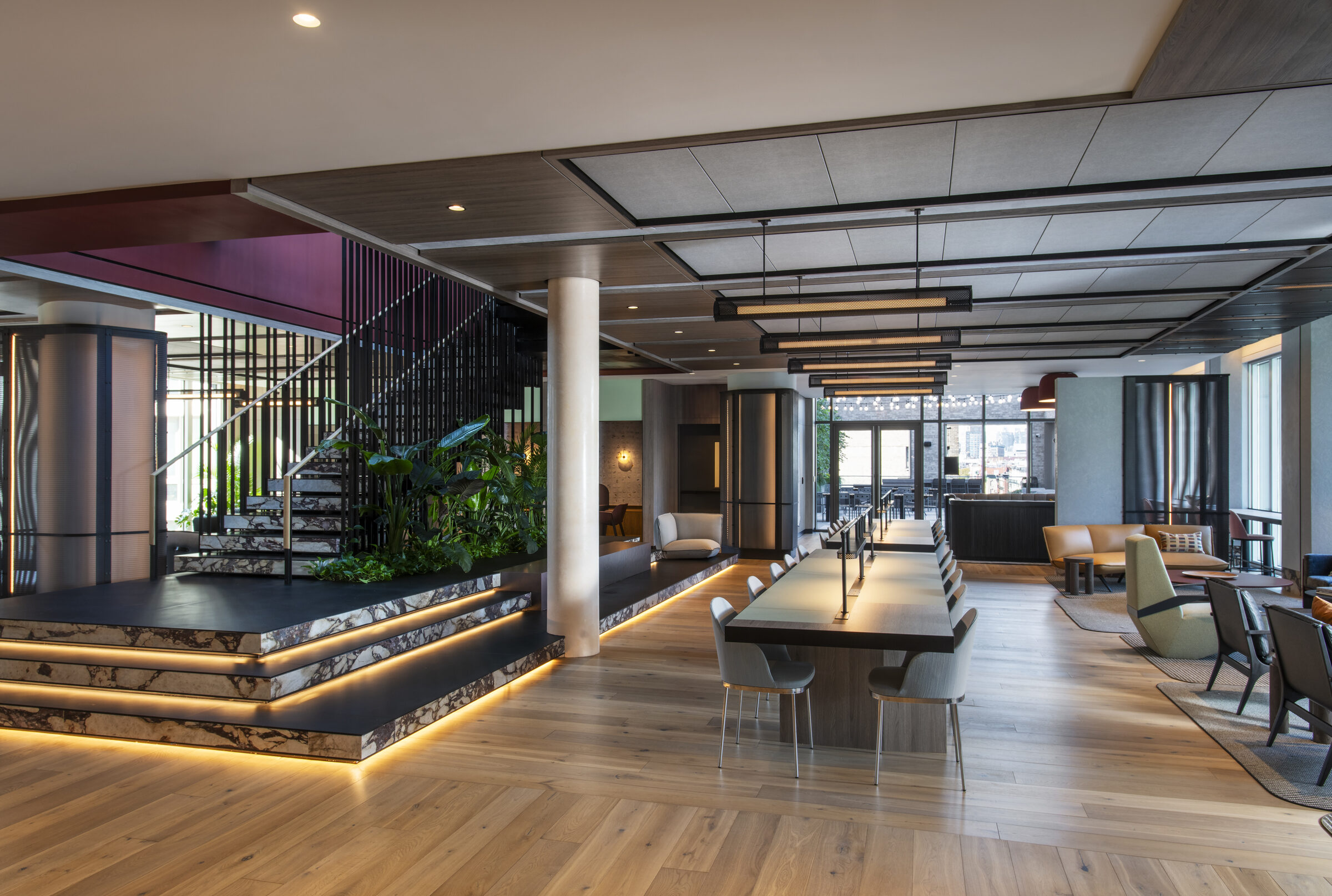 Resident lounge at The Suffolk with a staircase, seating areas, and worktables